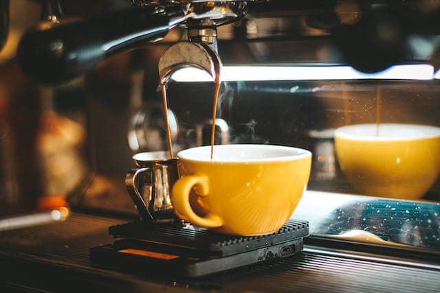 a fancy coffee machine making espresso into a yellow mug
