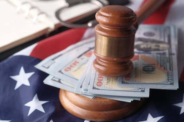 a judge’s gavel on top of cash and an American flag