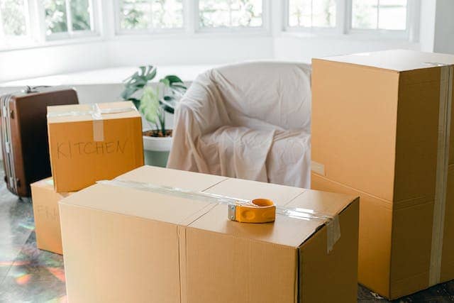 a bunch of moving boxes and covered furniture in a living room