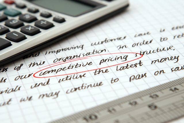 a calculator resting on a document with the words competitive pricing circled in red