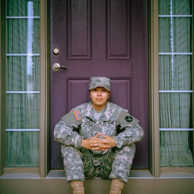 military service member sitting in front of their house